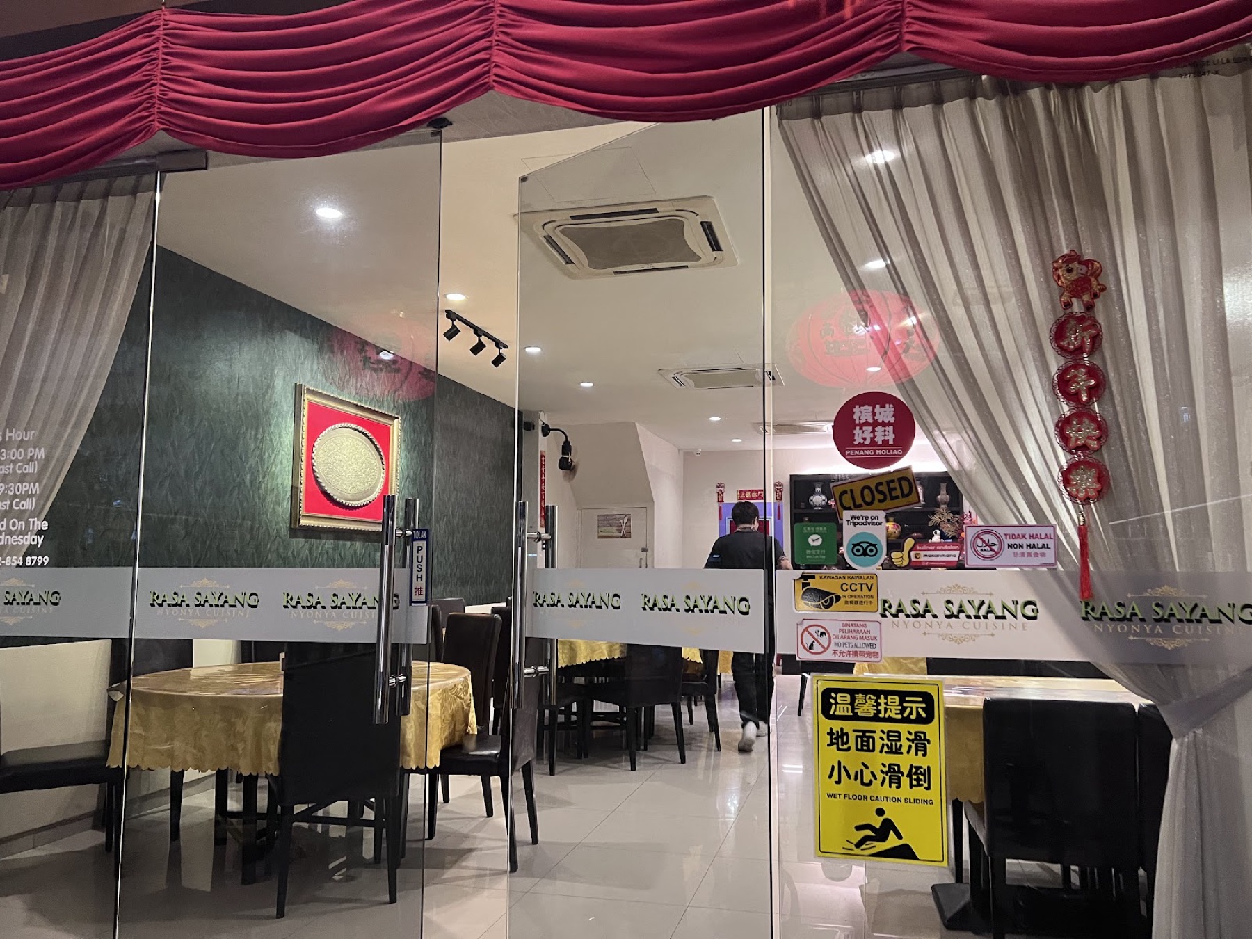 Etched-glass entrance doors marked Rasa Sayang with red drapery and gold tablecloths beyond