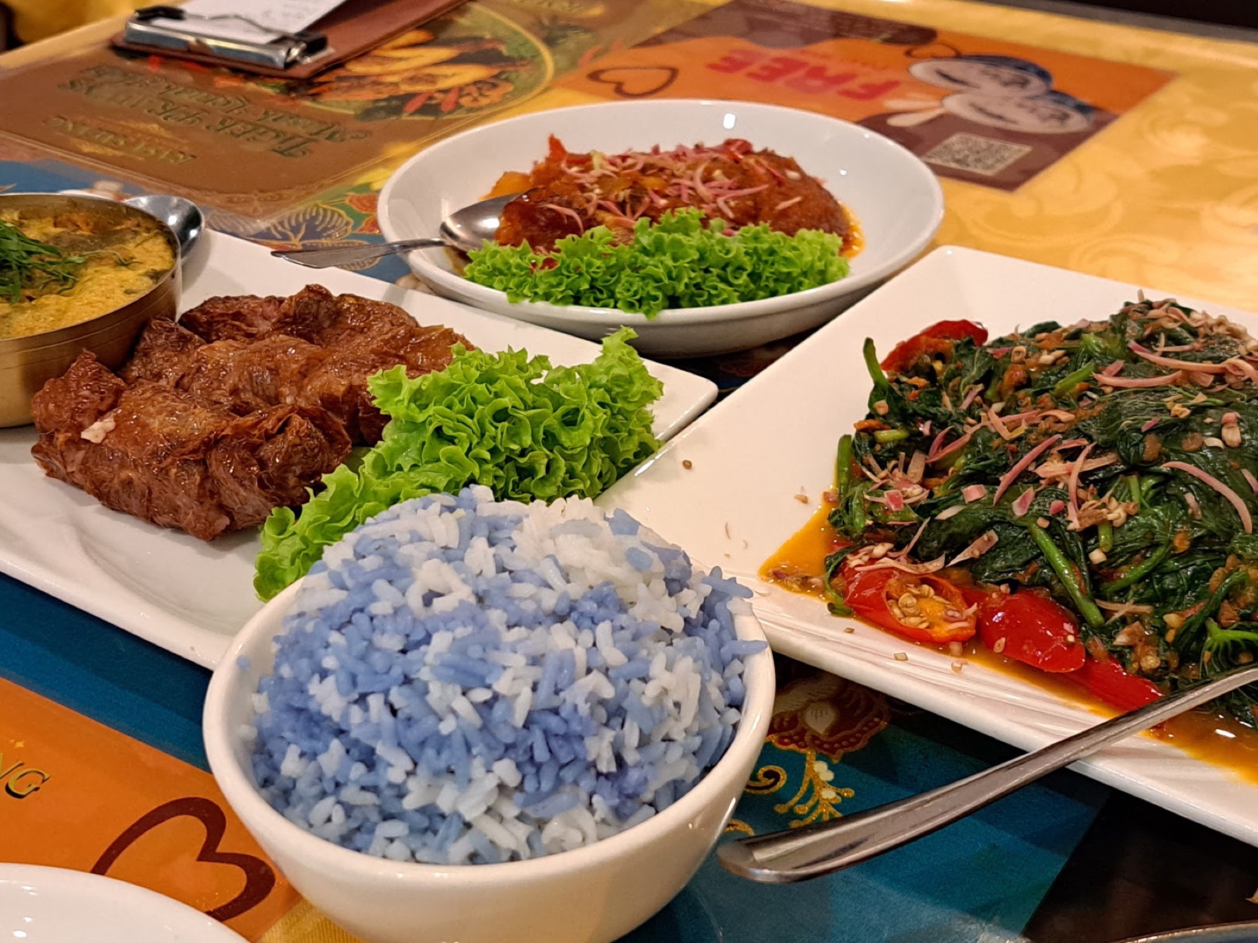 Butterfly-pea blue fragrant rice beside sambal kangkung and braised beef on a bright Peranakan table