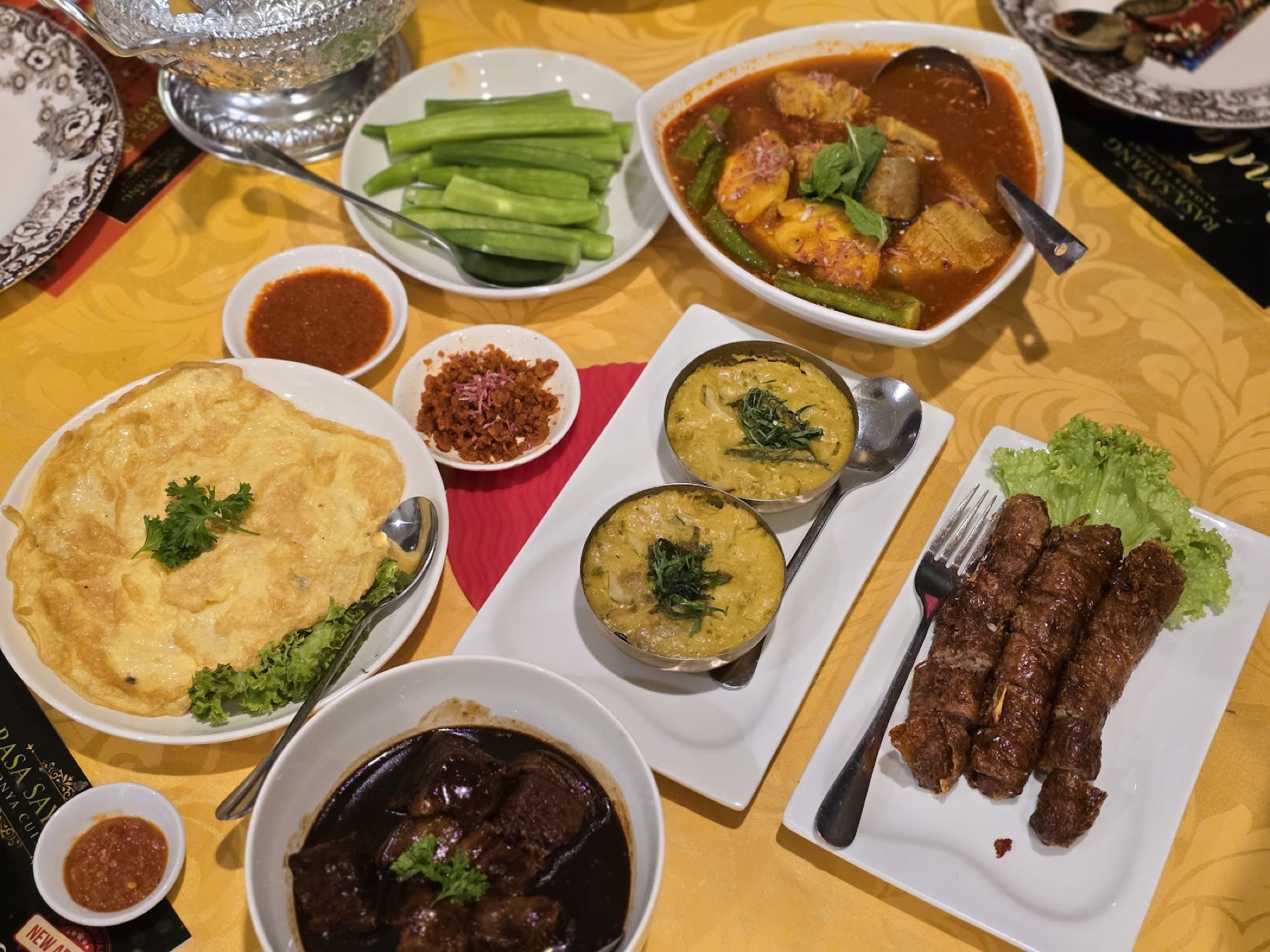 A top-down Nyonya banquet spread — omelette, pineapple curry, lor bak rolls and braised pork